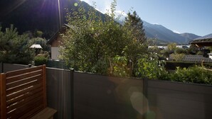 A wooden deck with a view of a mountain and a village. - Spacious Central Apartment with Terrace (Chamonix-Mont-Blanc)