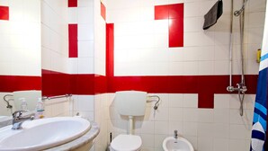 Un baño con lavamanos, inodoro, bidé y ducha.