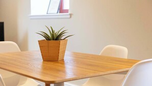 A wooden table with a potted plant in the center, surrounded by white chairs. - Granary Suite No3 - Donnini Apartments (Ayr)