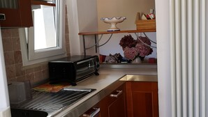 Una cocina compacta con armarios de madera, horno integrado, microondas y ventana.