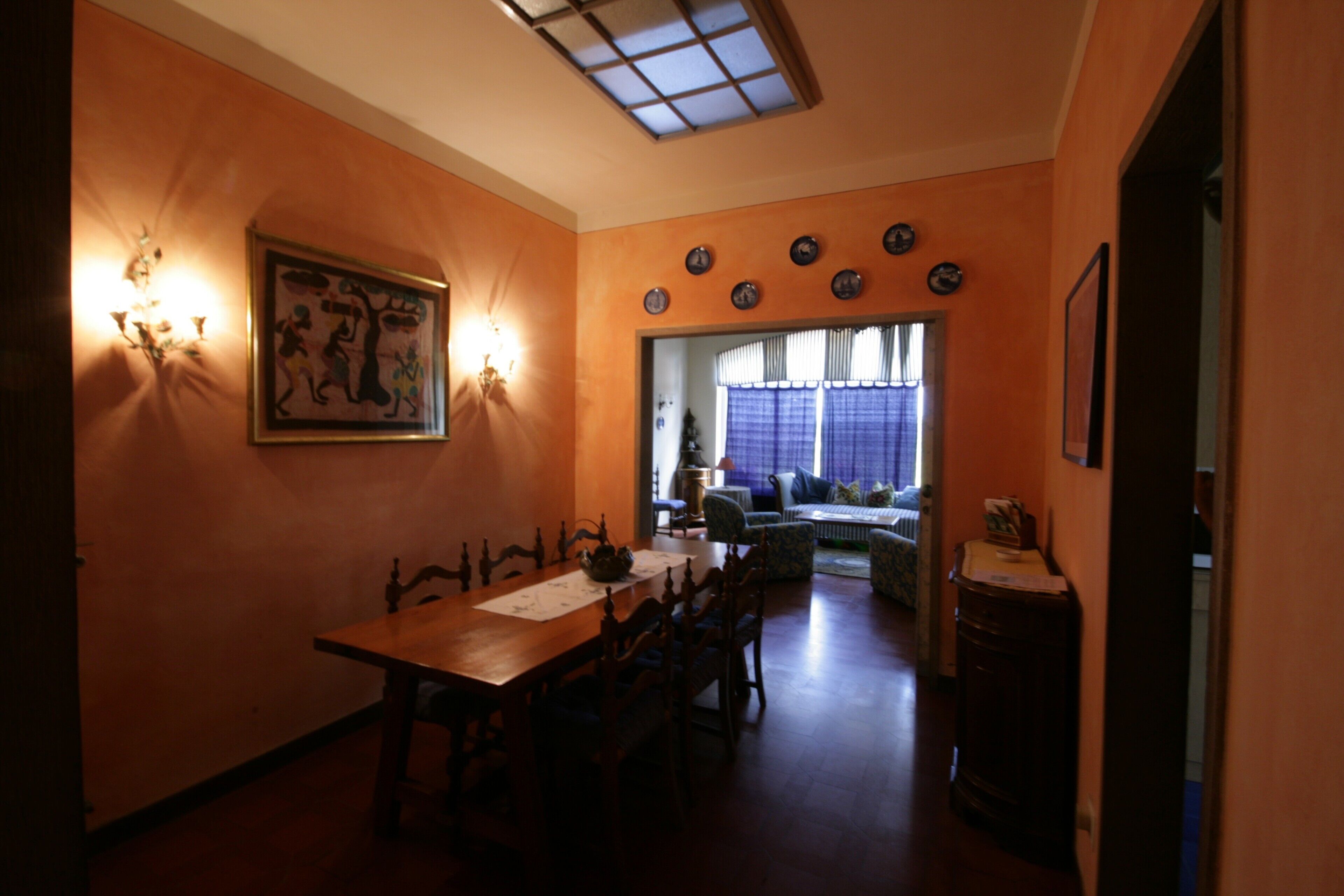 A dining area with a wooden table and chairs, a wall-mounted light fixture, and a ceiling skylight.