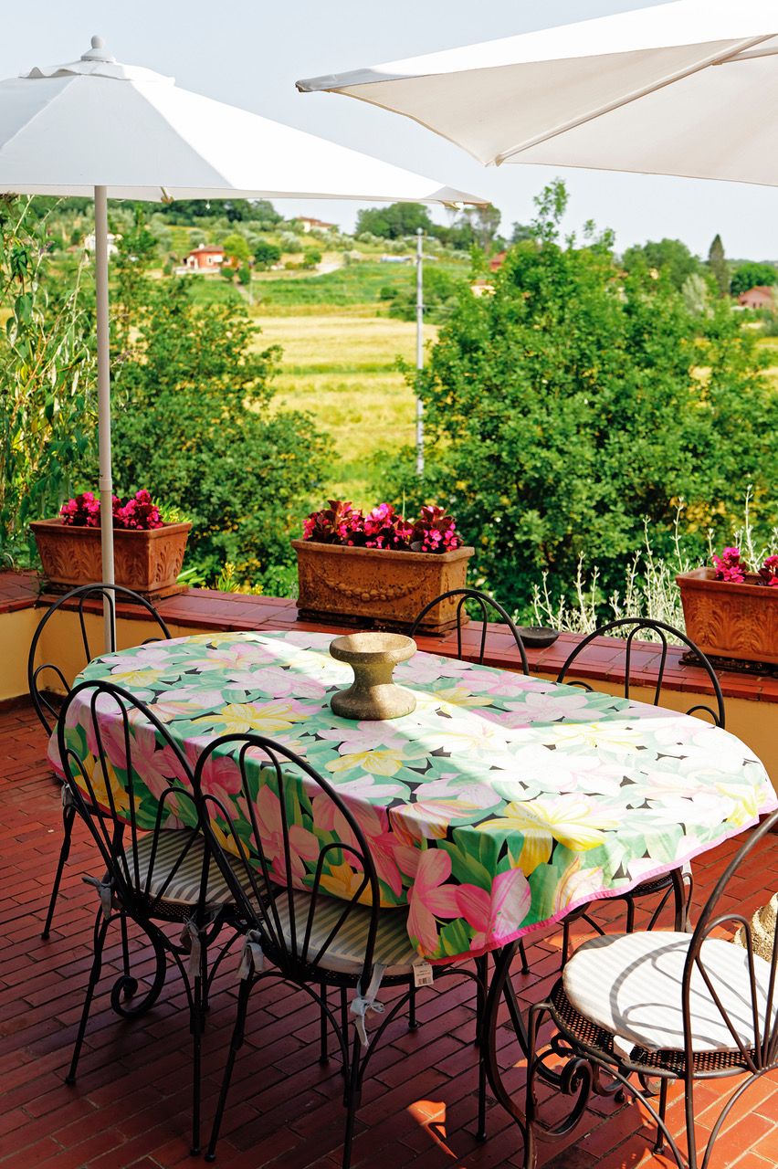 An outdoor patio with a round table, chairs, and potted plants.