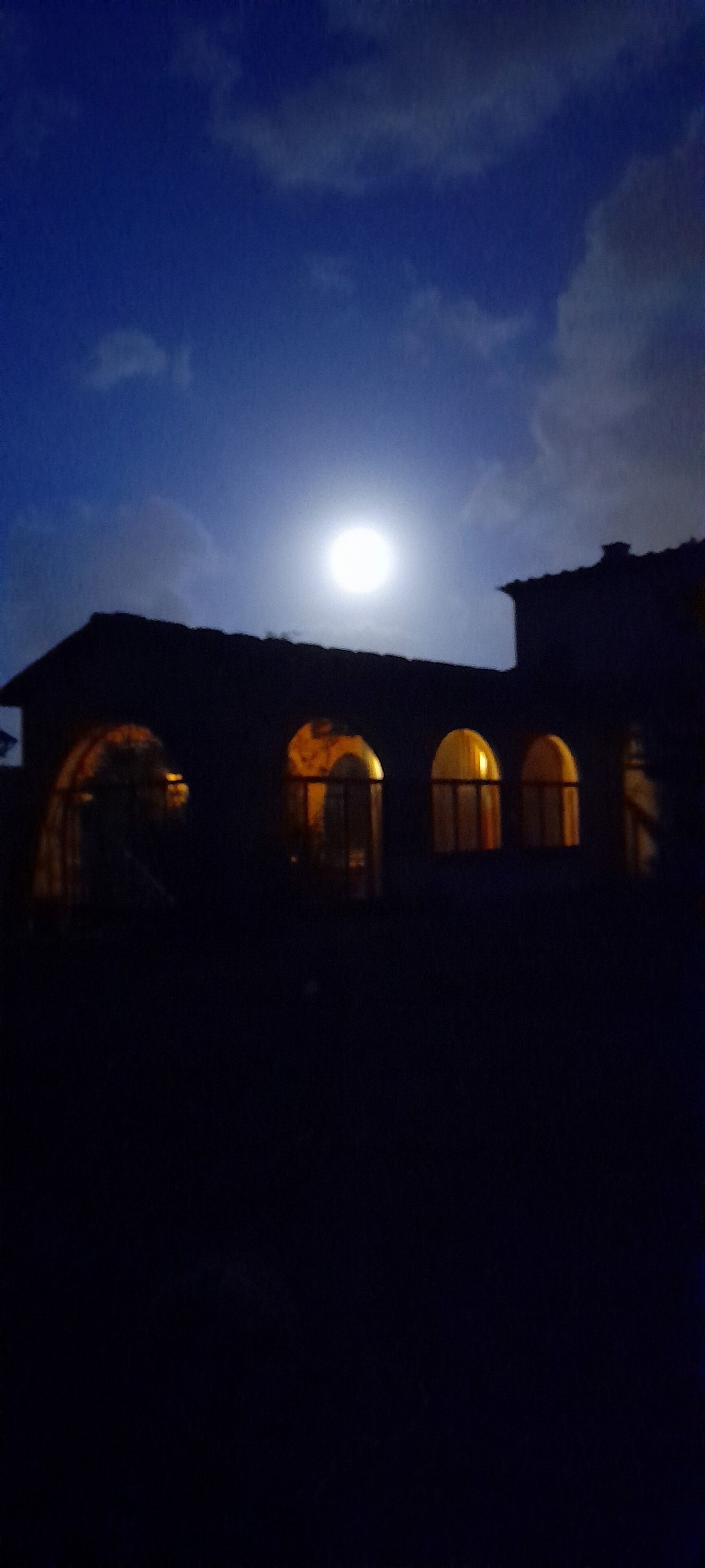 Un edificio con ventanas de arco y una luna en el cielo.