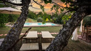 Un patio trasero con piscina, dos sillas reclinables y una zona de comedor con mesa y sillas.