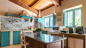 Una cocina con armarios verde azulado, una mesa de madera y una planta en maceta.