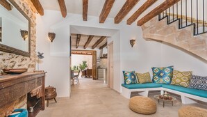 A cozy interior with a wooden staircase, a blue sofa with patterned cushions, and a rustic wooden table with a blue bowl. - Can Bons Aires by SunVillas Mallorca (Pollença)