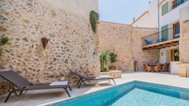 A pool area with stone walls, lounge chairs, and a dining area with outdoor furniture. - Can Bons Aires by SunVillas Mallorca (Pollença)