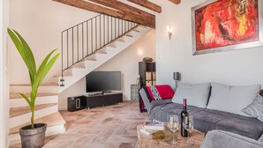 A living room with a staircase, a sofa, a coffee table, and a TV. - Can Bons Aires by SunVillas Mallorca (Pollença)