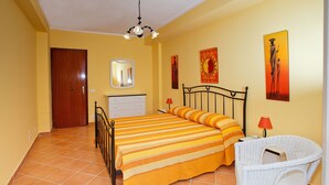 A bedroom with a bed, a chair, a dresser, and a door. - Apartment Neptune at the beach with a sea view - Letojanni, Sicily (Letojanni)