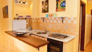 A compact kitchen with a built-in stove, sink, and a small refrigerator. - Apartment Neptune at the beach with a sea view - Letojanni, Sicily (Letojanni)