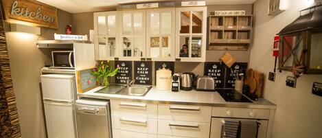 Una cocina moderna con armarios blancos, microondas integrado, refrigerador y cafetera.