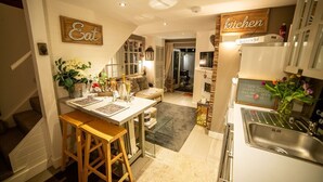 Une cuisine compacte avec un coin repas, un escalier et une vue sur le salon.