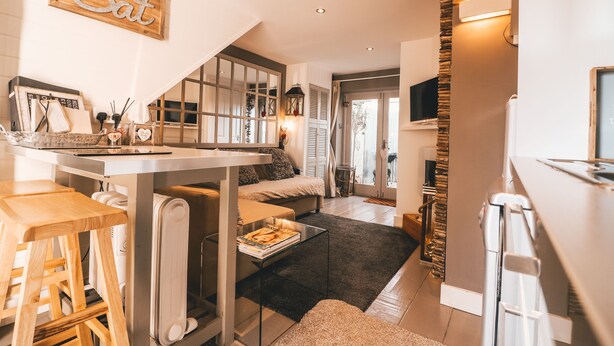 Une cuisine compacte avec un coin repas, un petit tabouret de bar et une table basse.
