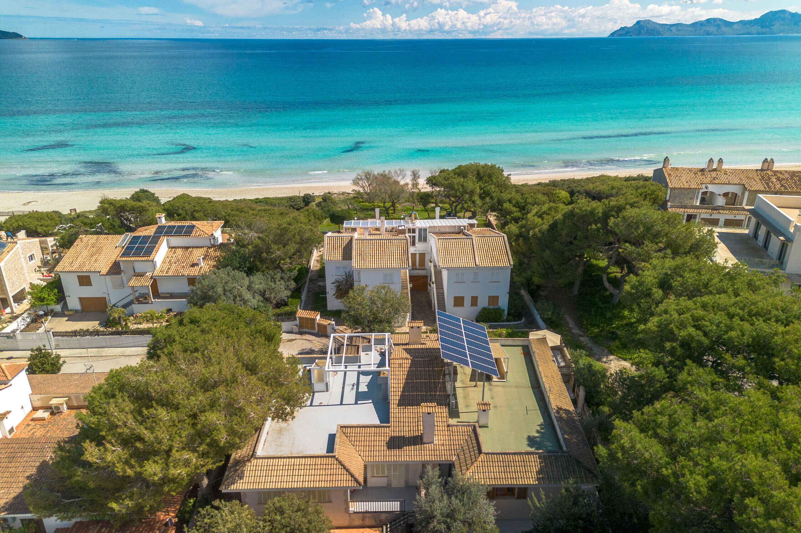 A coastal residential area with houses featuring solar panels and a view of the sea.