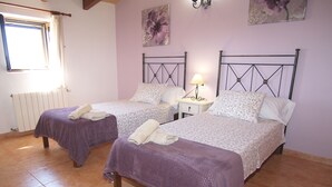 Un dormitorio doble con dos camas, una ventana, un radiador y una lámpara fijada a la pared.