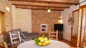 Un salón acogedor con una mesa redonda, un sofá, un televisor y una estantería.