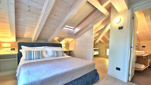 A bedroom with a large bed, wooden ceiling beams, and a skylight.