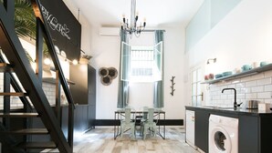 Une cuisine moderne avec un coin repas, un lave-linge et un escalier.