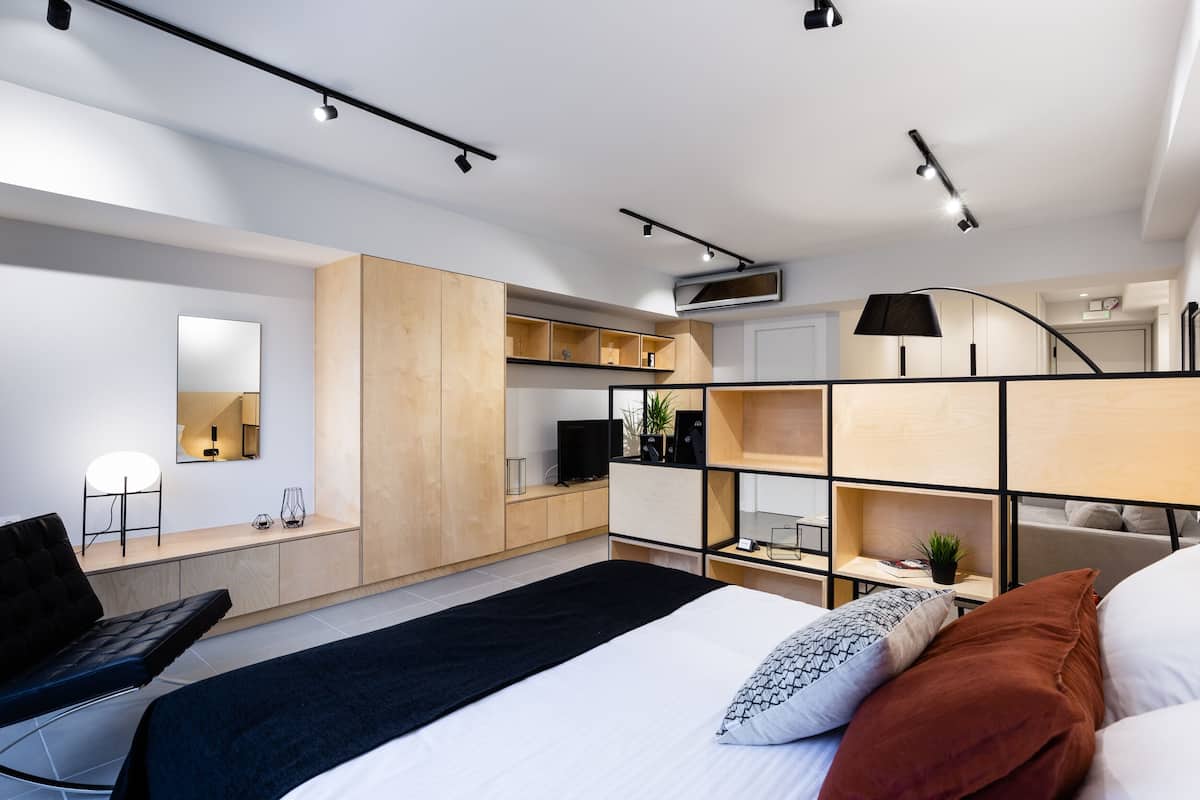 A modern bedroom with a bed, a desk, and built-in shelving.