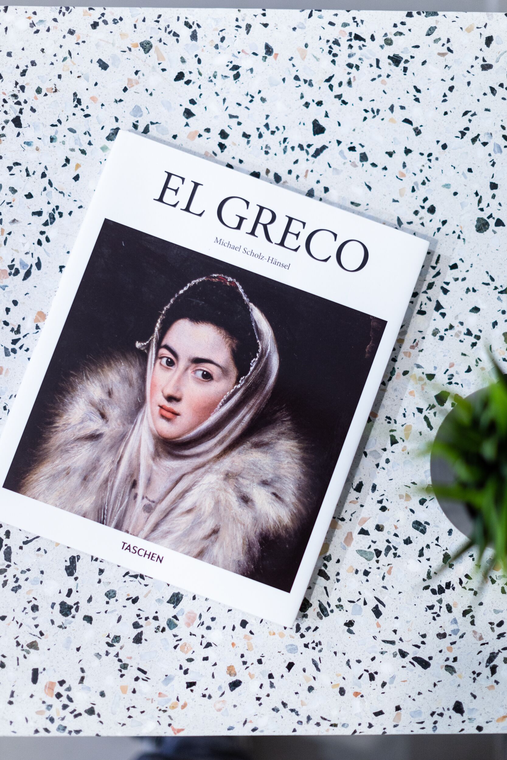 Un libro titulado "EL GRECO" de Michael Scholz-Hansel sobre un suelo de terrazo.