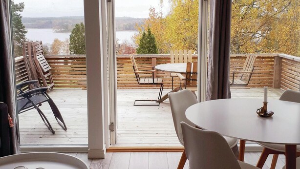 A deck with a table and chairs, overlooking a lake and autumn foliage. - Nice home in Skillingaryd with kitchen (Skillingaryd)