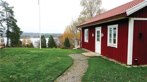 A red building with a white door and windows, a grassy yard, and a path leading to the entrance. - Nice home in Skillingaryd with kitchen (Skillingaryd)