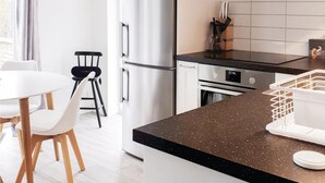 A modern kitchen with a stainless steel refrigerator, a black countertop, and a dining area with white chairs and a table. - Nice home in Skillingaryd with kitchen (Skillingaryd)