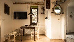 Ein Zimmer mit Esstisch aus Holz, Bänken, einem an der Wand befestigten Fernseher, einem Fenster mit Aussicht und einem Spiegel.