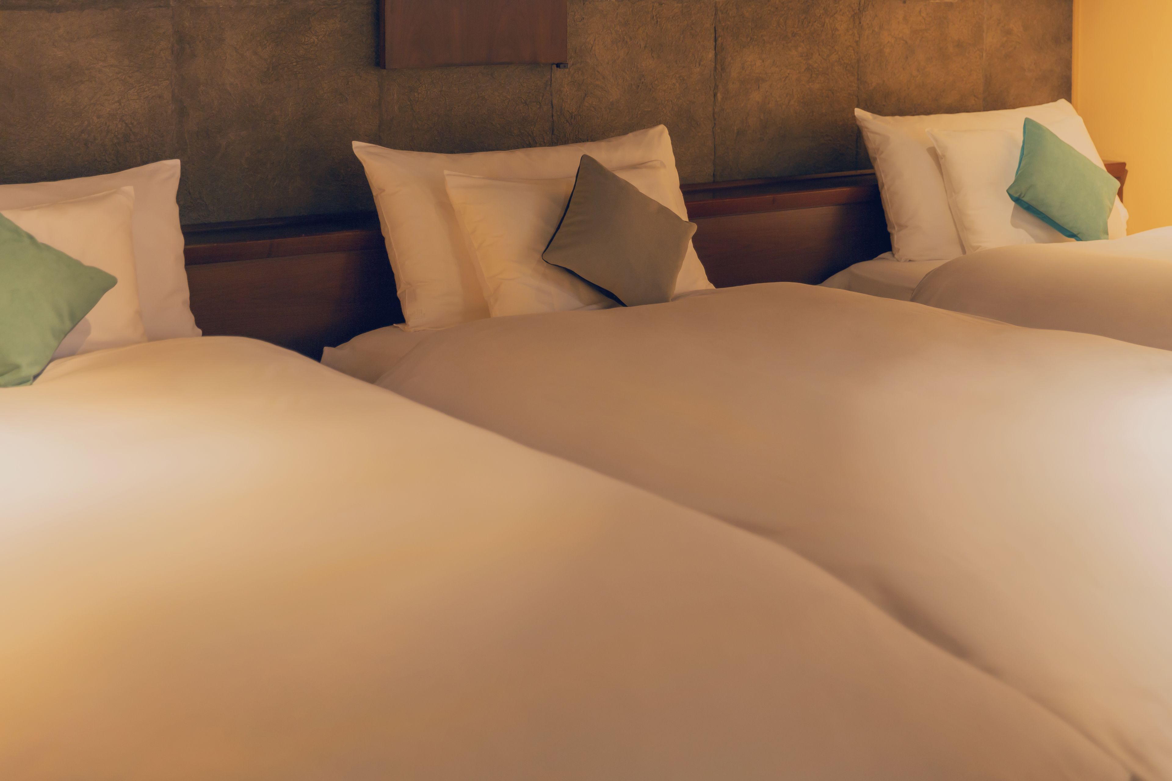 A hotel room with three beds, each with white bedding and pillows.