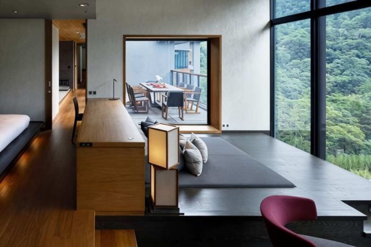 A modern room with a large window, a desk, and a seating area.