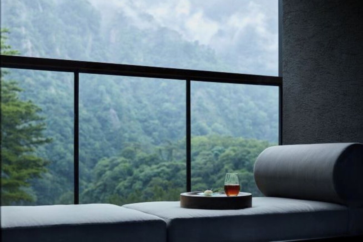 A modern room with a large window overlooking a forested mountain range.