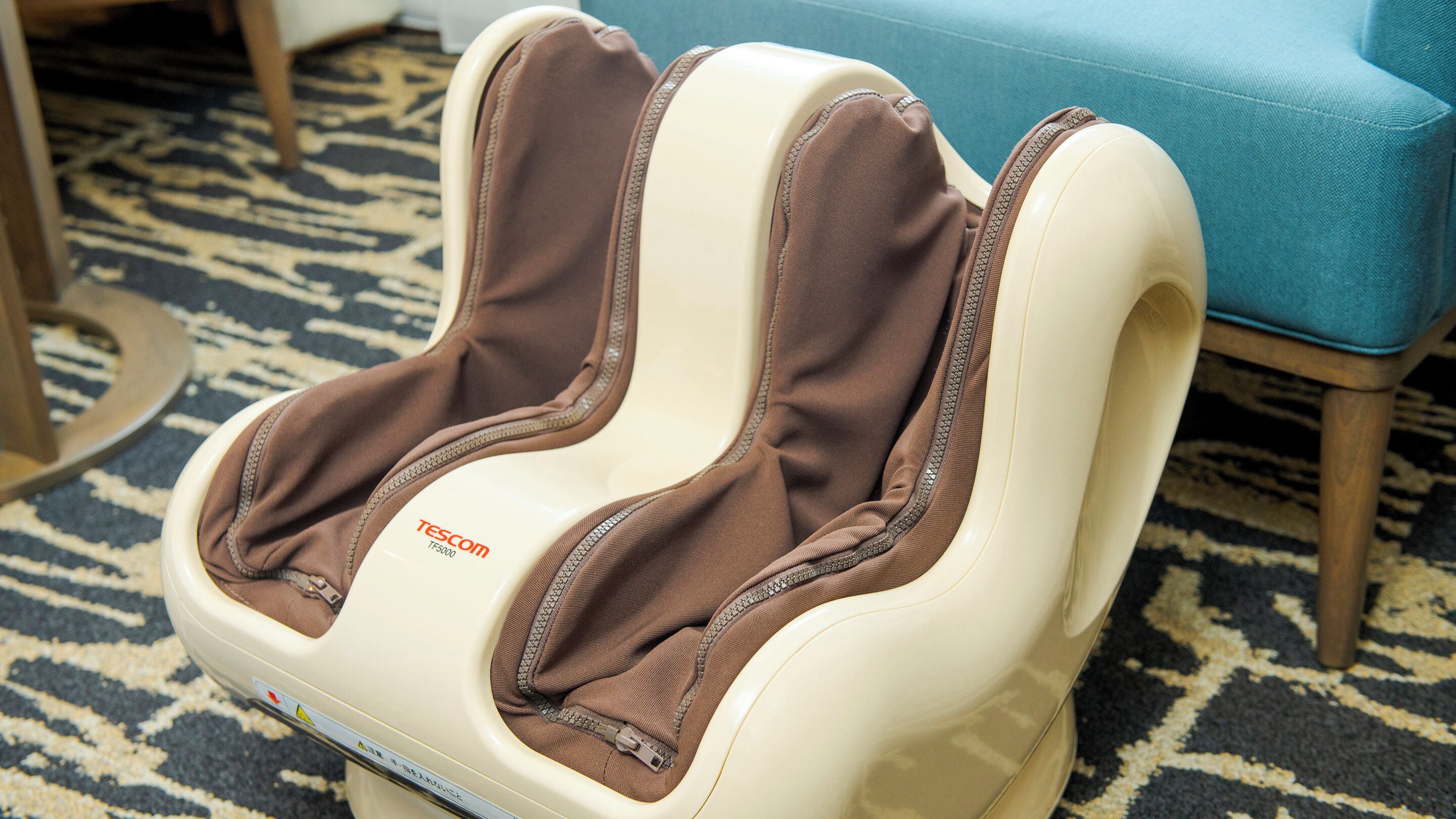 A massage chair with a control panel labeled "TESCOM TF5000" on a patterned carpet.