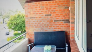 A balcony with a brick wall, a table with chairs, and a view of the street. - Holiday apartment directly on the beach of the North Sea and still central in Bensersiel (Bensersiel)