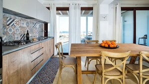 A modern kitchen with a tiled backsplash, wooden cabinets, and a dining area with a wooden table and chairs. - Villa Ulivo for 8 People in Sicily, Pool, Sea View, Garden, Wifi and A/C (Reitani)
