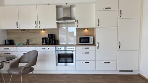 Una cucina moderna con mobili bianchi, elettrodomestici in acciaio inossidabile e pavimento in legno.