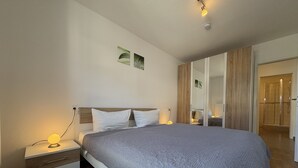 Una camera da letto moderna con un letto grande, comodini, un armadio e un angolo doccia.