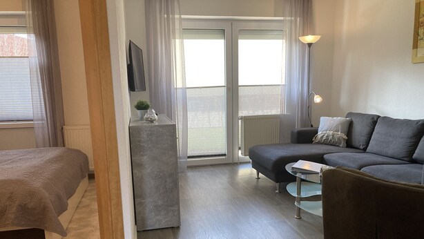 A modern living room with a sofa, a glass coffee table, and a bed. - The "Seepferdchen" in Haus Meeresglück, close to the beach and central! (Dahme)