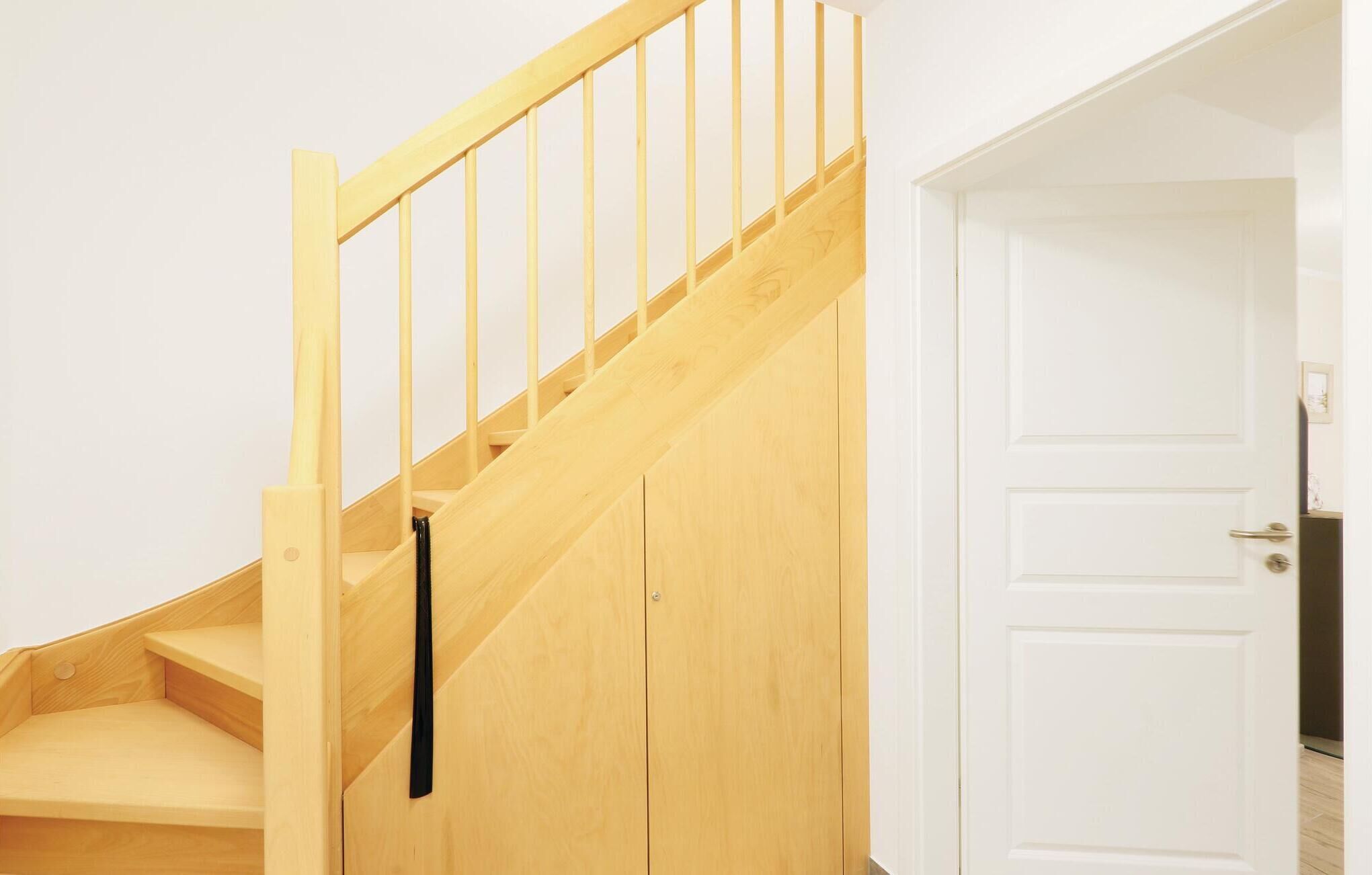 Un escalier en bois menant à une porte blanche.