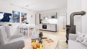 Un salon moderne avec un canapé, une table basse sur laquelle on a posé des fruits et un téléviseur.
