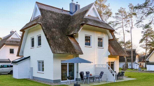 Une maison avec un toit à forte pente, un patio couvert avec des meubles d’extérieur et un garage.