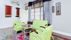 A room with a green sofa set, a small round table, and a patterned rug. - Hotel O Jalan Jenderal Sudirman Near Imam Bonjol Square Formerly Nelvi Guest House (Padang)