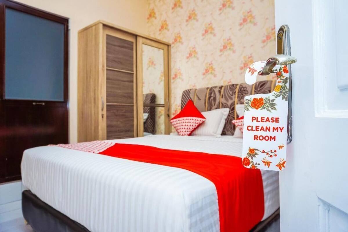 A hotel room with a bed, a wardrobe, a television, and a sign requesting room cleaning.