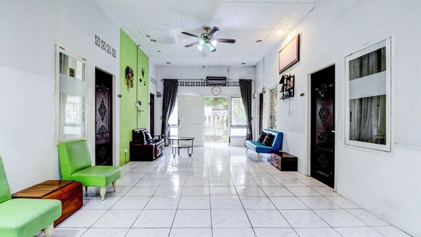 A hallway with green and blue seating, a ceiling fan, and a tiled floor. - Hotel O Jalan Jenderal Sudirman Near Imam Bonjol Square Formerly Nelvi Guest House (Padang)