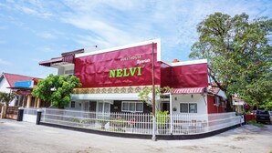 A building with a maroon facade and a sign that reads "GUESTHOUSE Syariah NELVI". - Hotel O Jalan Jenderal Sudirman Near Imam Bonjol Square Formerly Nelvi Guest House (Padang)