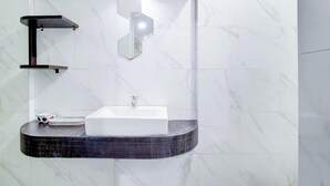 A modern bathroom with a white marble wall, a white sink, and a dark wood vanity. - Hotel O Jalan Jenderal Sudirman Near Imam Bonjol Square Formerly Nelvi Guest House (Padang)
