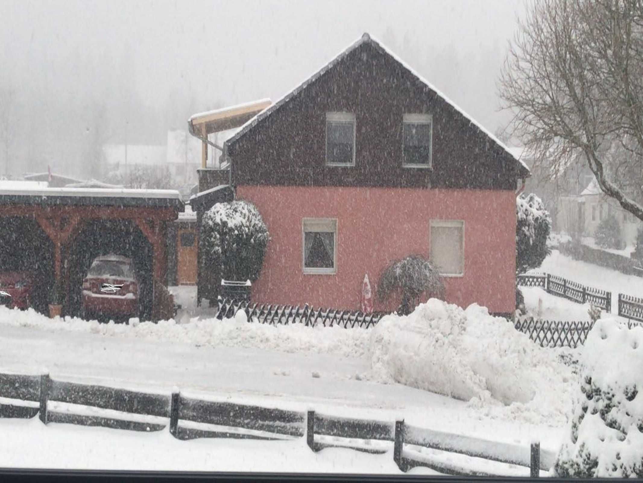 Ein rotes Gebäude mit einem schwarzen Dach, umgeben von Schnee.