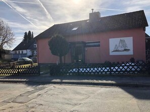 A pink building with a chimney, a tree in front, and a fence. - Private rental Ina - holiday room (Clausthal-Zellerfeld)