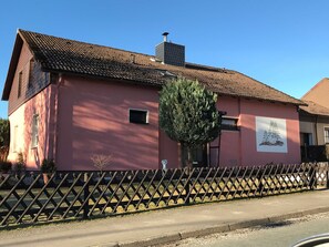 A pink building with a tiled roof, a small window, and a tree in front. - Private rental Ina - holiday room (Clausthal-Zellerfeld)