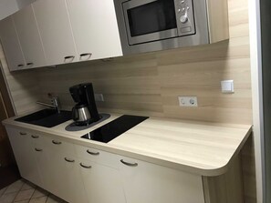 A kitchen with two sinks, a coffee maker, a microwave, and cabinets. - Private rental Ina - holiday room (Clausthal-Zellerfeld)