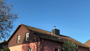 A building with a red facade, a tiled roof, and a chimney.